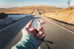 Compass in hand, with mountain road in the background
