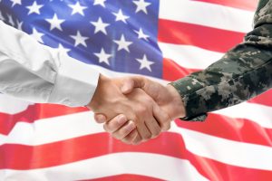 Soldier,And,Civilian,Shaking,Hands,On,Usa,Flag,Background